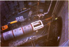 ‘Little Ceel’ TBM almost at Brookland Close. The rams behind the tunnel segments are pushing the TBM through with the linings behind.
The TBM comes out at the other end leaving the bore fully lined with the concrete segments.
The 7m tunnel entrance is being opened up in readiness for the big  TBM after the removal of the 2m equipment is lifted out of the way.